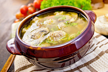 Image showing Soup with meatballs and spoon in pottery on dark board