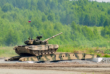 Image showing T-80 tank drives on bridge induced through obstacle