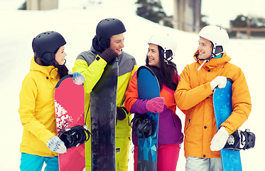 Image showing happy friends in helmets with snowboards talking