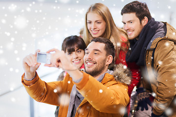 Image showing happy friends with camera on skating rink