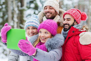 Image showing smiling friends with tablet pc in winter forest