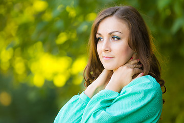 Image showing Portrait of a girl hugging his neck on a background of green foliage