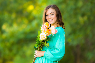 Image showing Portrait of a girl with a bouquet of roses on the background blurred foliage