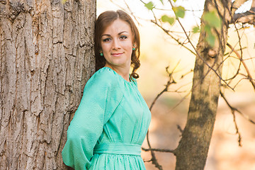 Image showing Portrait of a girl leaning on a tree in the woods