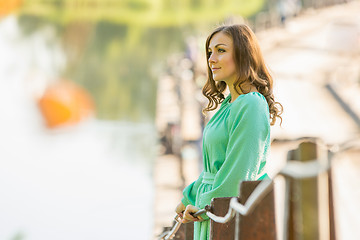 Image showing Beautiful girl standing on the bridge over the river and looks into the distance