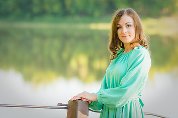 Image showing Portrait of a girl on the bridge over the river in the early morning