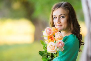 Image showing Portrait of a girl with a bouquet of roses on a background blur forest