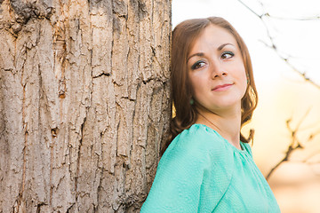 Image showing Portrait of a girl leaning against a tree