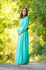 Image showing A girl in a long dress against a background of blurred forest