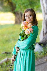 Image showing Portrait of a girl with a bouquet of roses walking in the woods
