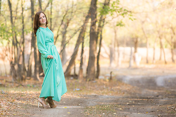 Image showing A girl in a long dress walking on the road turned