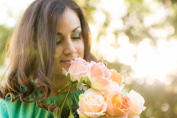 Image showing A young girl looks at a bouquet of roses