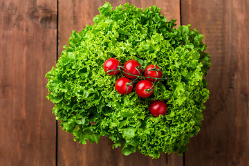 Image showing lettuce salad and cherry tomatoes on a wood background