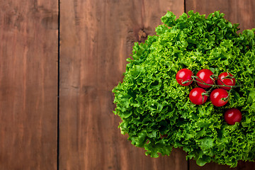 Image showing lettuce salad and cherry tomatoes on a wood background