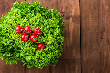 Image showing lettuce salad and cherry tomatoes on a wood background