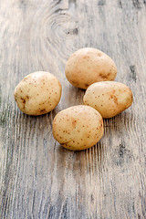 Image showing raw baby potatoes on wooden background