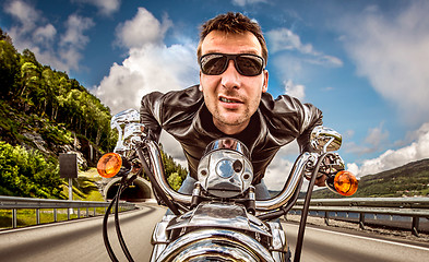 Image showing Funny Biker in sunglasses and leather jacket racing on mountain 