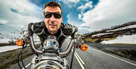 Image showing Funny Biker in sunglasses and leather jacket racing on mountain 