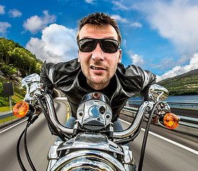 Image showing Funny Biker in sunglasses and leather jacket racing on mountain 