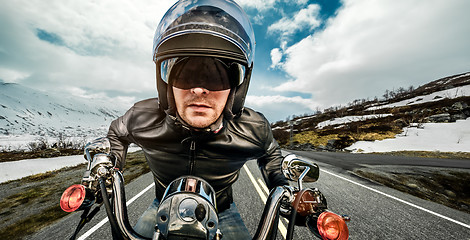 Image showing Biker in helmet and leather jacket racing on mountain serpentine