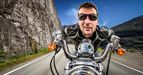 Image showing Funny Biker in sunglasses and leather jacket racing on mountain 