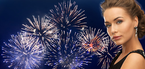 Image showing beautiful woman wearing earrings over firework