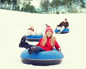 Image showing group of happy friends sliding down on snow tubes