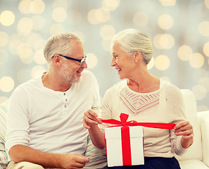 Image showing happy senior couple with gift box at home