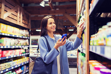 Image showing happy young woman with smartphone in market