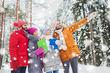 Image showing smiling friends with tablet pc in winter forest