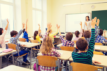 Image showing group of school kids raising hands in classroom