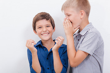 Image showing Teenage boy whispering in the ear a secret to friendl on white  background