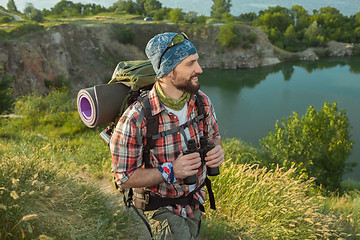 Image showing Young caucasian man with backpack walking on the top of hill