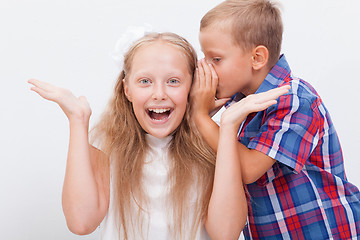 Image showing Teenage boy whispering in the ear a secret to teen girl on white  background