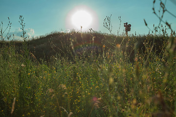 Image showing Young caucasian man with backpack walking on a green meadow