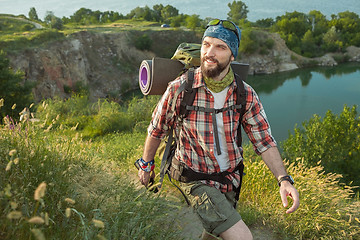 Image showing Young caucasian man with backpack walking on the top of hill