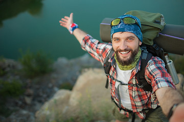 Image showing fully equipped tourist smiling on the background of lake