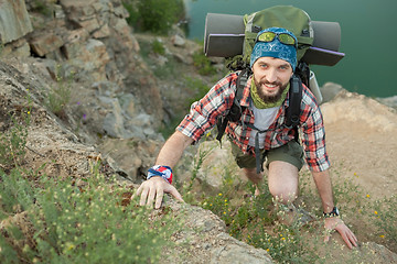 Image showing Young caucasian man with backpack climbing the rock