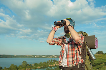 Image showing Young caucasian man with backpack standing on the top of hill