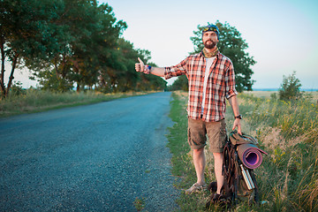 Image showing Young  caucasian tourist hitchhiking along a road.