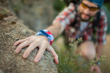 Image showing Young caucasian man with backpack climbing the rock