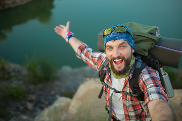 Image showing Young caucasian man with backpack standing on the top of hill