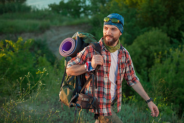 Image showing Young caucasian man with backpack walking on the top of hill