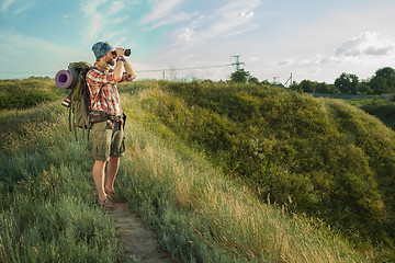 Image showing Young caucasian man with backpack standing on the top of hill