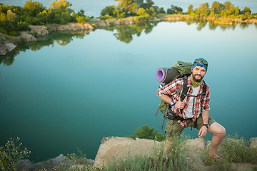 Image showing Young caucasian man with backpack climbing the rock