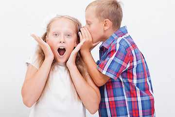 Image showing Teenage boy whispering in the ear a secret to teen girl on white  background