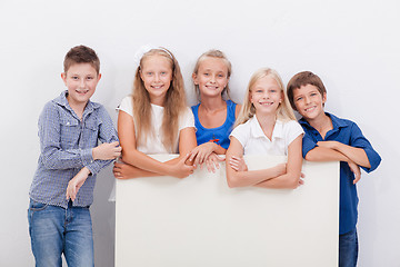 Image showing Happy smiling group of kids, boys and girls, showing board 