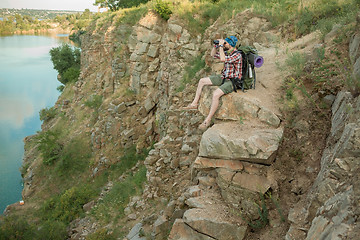 Image showing Young caucasian man with backpack sitting on the top of hill