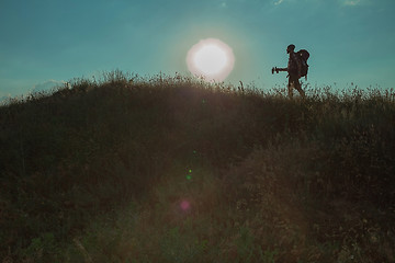 Image showing Young caucasian man with backpack walking on a green meadow