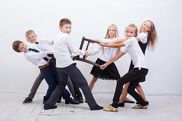 Image showing Kids playing tug of chair - girls versus boys,